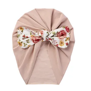 Detail view of pink baby turban hat featuring a large floral bow and soft knit fabric