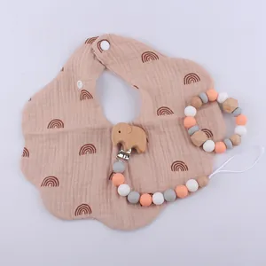 Pink cotton bib with rainbow print and elephant wooden pacifier clip for infants