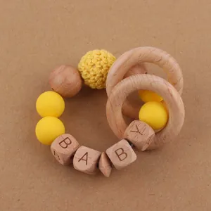 Gros plan sur l'anneau de dentition bébé en bois de hêtre avec perles en silicone jaune