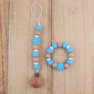 Detail of blue silicone rose teether bracelet and matching pacifier clip with wooden beads