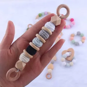 Detail of wooden baby teether with crochet balls and beech wood rings for sensory play