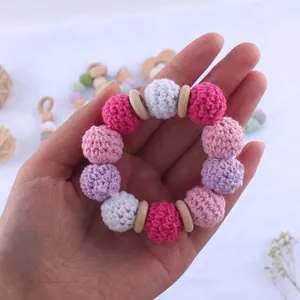 Detail of crochet baby teether ring with pink macaron yarn balls and beech wood rings