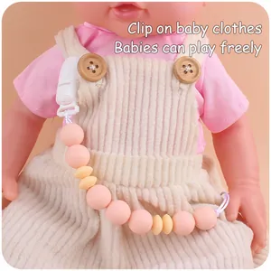 Nahaufnahme der Schnullerkette aus Silikon in Rosa und Gelb an einer Baby-Latzhose