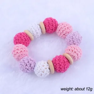 Detail of crochet macaron balls and natural beech wood teething ring for infants