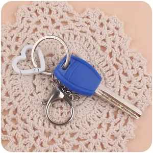Close-up of white heart-shaped clasp and blue key accessory on a white lace background