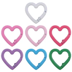 Close-up of heart-shaped alloy spring ring hooks in seven assorted lacquer colors