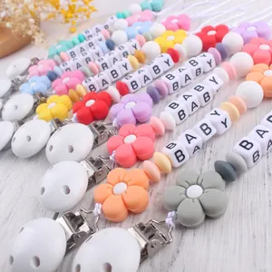 Colorful silicone pacifier clips with flower beads and baby letter beads on wood