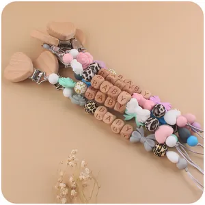 Detailed macro view of baby pacifier clip with beech wood heart and silicone bow beads
