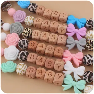 Close-up of silicone pacifier clips with beech wood beads and baby letter engraving