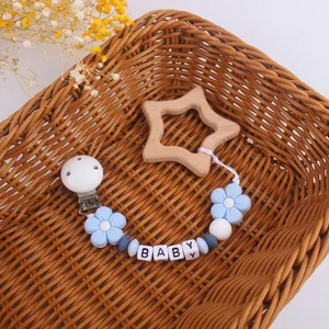 Baby pacifier clip with blue flower teether and wooden beads in a cozy basket