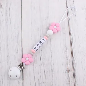 Detail of baby pacifier clip with pink flower beads and white BABY letter squares