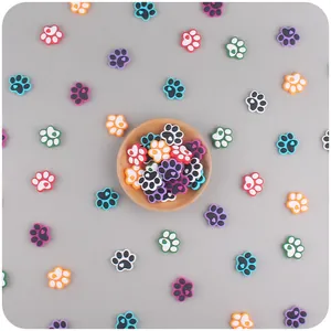 Close-up of colorful silicone dog paw charms with heart details in a wooden bowl