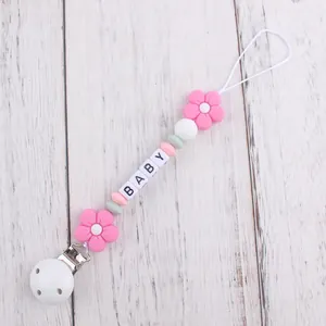 Close-up of silicone pacifier clip with pink flowers, macaron beads and BABY letter cubes