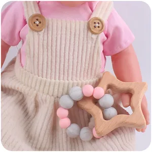 Detail of wooden star teether with pink and grey silicone beads held by a doll