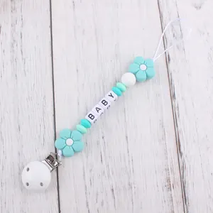 Close-up of silicone pacifier clip with mint green beads and BABY letter blocks