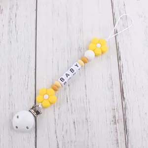 Detail of baby pacifier clip with yellow silicone flowers and BABY letter beads