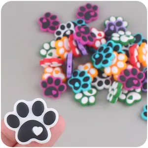 Silicone paw print teething charm with heart detail shown for scale on a fingertip