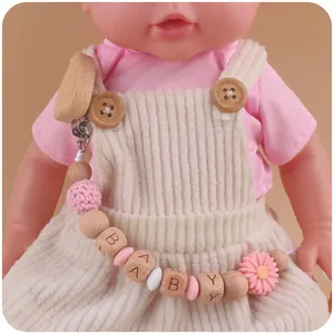 Detail of wooden baby pacifier clip with heart shape and pink daisy silicone beads