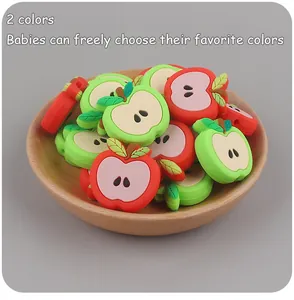 Detail of red and green apple silicone teething beads in a wooden dish for DIY clips