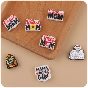 Detail view of silicone charms featuring Mama and sport themes on a wooden tray
