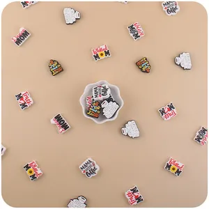 Close-up of PVC charms featuring Dance MOM and MAMA NEEDS Coffee phrases in a white bowl