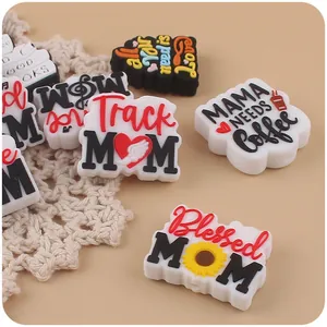 Close-up of PVC shoe charms with MOM and heart designs on a decorative background