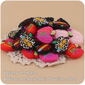 Macro detail of apple-shaped silicone beads with Teacher engraving and leopard patterns