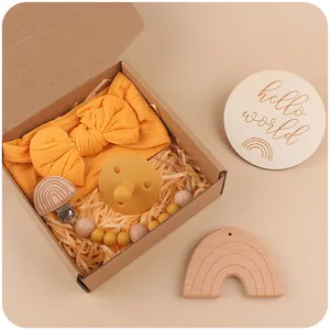 Infant gift set with yellow bow headband, silicone pacifier, and wooden clip in a kraft box