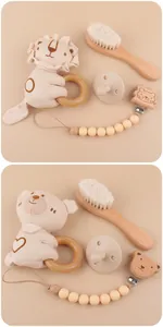 Detail of wooden baby gift set with lion rattle, soft hairbrush, and pacifier clip