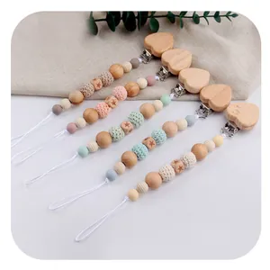 Detail of five DIY pacifier clips with beechwood heart clips and colorful crochet beads
