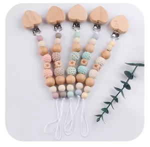 Flat lay of five pacifier clips with silicone beads, beech wood hearts and star carvings