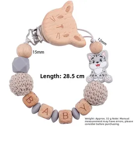 Dettaglio della catenella portaciuccio in faggio con perle in silicone e lettere BABY