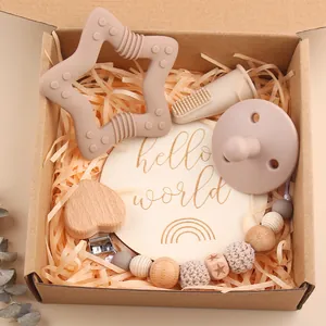 Detail showing silicone star teether, pacifier, and wooden clip in a gift box