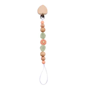 Detail of baby pacifier clip with beech wood heart and daisy silicone beads on white base