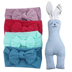 Baby gift set with four stretchy knitted bow headbands and a cute wooden bunny toy