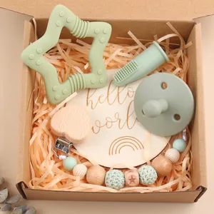 Sage green baby gift set with silicone teether, pacifier, and wooden clip in a craft box
