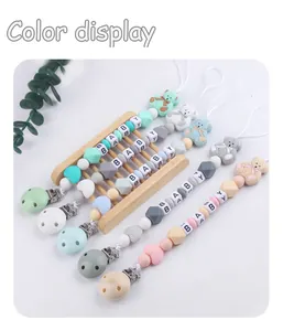 Detail of baby pacifier clips with silicone beads, wooden display and cartoon bear