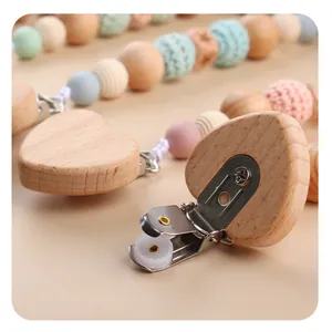 Detail of wooden pacifier clip featuring natural heart-shaped block and silicone beads