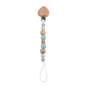 Detail of baby pacifier clip featuring heart wood clip and mint crochet beads