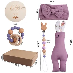 Baby gift set with rabbit pacifier clip, bow headband, rattle, and doll in a kraft box
