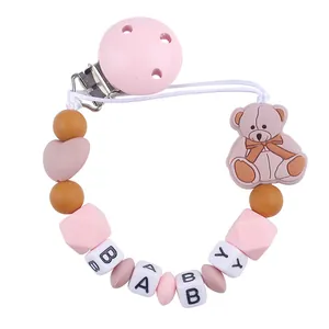 Detail of pink silicone pacifier clip featuring cartoon bear and BABY letter beads
