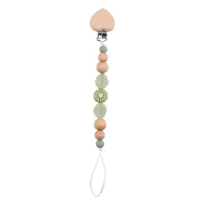 Detail of baby pacifier clip with beech wood heart and sage green silicone beads