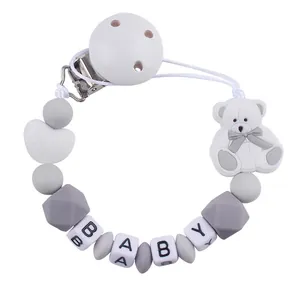 Detail of baby pacifier clip featuring white cartoon bear and silicone letter beads