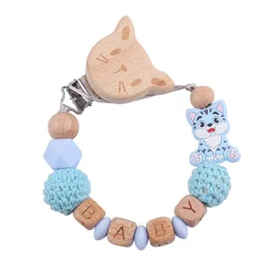 Dettaglio della catenella portaciuccio in legno con gatto, perle in silicone blu e cubi BABY