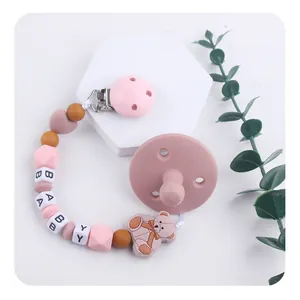 Silicone pacifier set with bear clip and BABY letter beads on a decorative stand