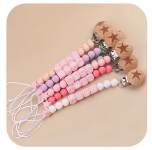 Detail of pink silicone and beech wood baby pacifier clips with star beads and BABY letters