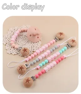 Detail view of silicone baby pacifier clips with beech wood stars and baby letter beads