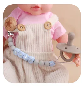 Detail of baby pacifier chain with silicone beads and beech wood clip on a doll