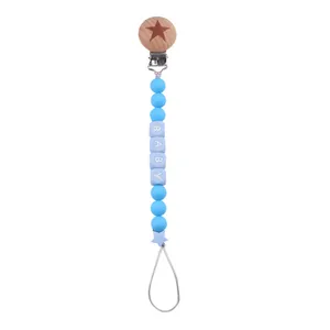 Detailed view of silicone baby pacifier clip with beech wood star buckle and BABY letters