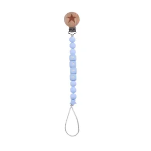 Detail of wooden pacifier clip with blue silicone beads and BABY letter beads